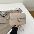 Close-up of beige lychee-grain leather handbag with golden metal twist lock and handle - Khaki
