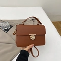 Detail of caramel lychee leather handbag with a round golden twist lock and top handle - Brown