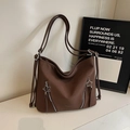 Detail shot of a brown leather tote bag featuring star-shaped zippers and front pockets - Brown