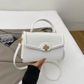 Close-up of white pebble leather handbag with gold metal clasp and circular handle - White
