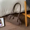 Close-up of deep brown Boston bag with frosted texture and delicate ribbon bow details - Brown
