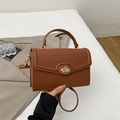 Detail of brown litchi pattern leather handbag with elegant golden oval twist lock - Brown