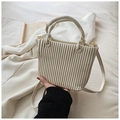 Detail of beige pleated bucket bag with woven handle on white fabric background - White