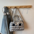 Bolso tote acolchado plateado con correas negras colgado en un ambiente cotidiano - Plateado