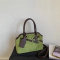 Close-up of green suede tote bag showing detailed stitching and silver hardware lock - Green