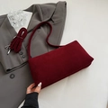 Detail van donkerrode suède kussentas op een grijs jasje voor een elegante herfstlook - Rood