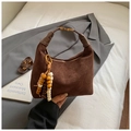 Deep brown suede crescent bag with quilted pattern and beaded tassel charm in hand - Brown