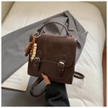 Macro shot of dark brown crossbody bag with dual silver buckles and wooden bead charm - Coffee With Pendant