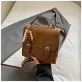 Detail view of a vintage contrast color handbag with wooden bead charm on a blazer - Brown with Pendant