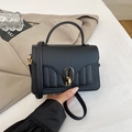 Detail of black pebbled leather handbag with gold oval twist lock and vertical stitching - Black