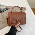 Detail of a brown lychee pattern leather handbag with an oval gold-toned metal lock - Brown