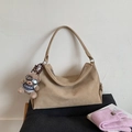 Detailansicht der beigen Wildleder-Umhängetasche mit Textur und süßem Bärenanhänger - Khaki Mit Anhänger