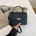 Detail of black pebbled leather handbag with golden twist lock held by a model - Black