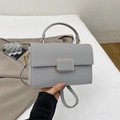 Detail view of grey litchi grain leather crossbody bag with gold metallic buckle and handle - Gray