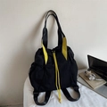 Detail showing the black nylon drawstring tote bag with contrasting yellow straps and buckles - Black