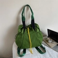 Green nylon drawstring tote bag with yellow accents shown in a study desk setting - Green