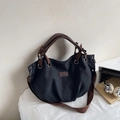 Vue détaillée du grand sac fourre-tout en toile noire avec poignées en cuir marron et rivets - Noir