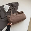 Brown frosted suede bucket bag with decorative buckle shown in a lifestyle commuter setting - Gray