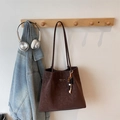 Dettaglio borsa tote in pelle marrone vintage con logo e ciondolo di perline sull'appendino - Caffè Con Pendente