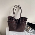 Detalle del bolso tote marrón oscuro con textura mate y cinturón decorativo en escena real - Marrón