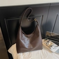 Detalle de la textura de cuero marrón oscuro y costuras de este bolso hobo de gran tamaño - café