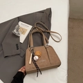 Detailaufnahme der khakifarbenen Retro-Umhängetasche mit Baseball-Anhängern und Logo-Prägung - Khaki Mit Anhänger