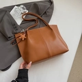 Brown leather tote bag with star charm and shoulder straps on a gray suit jacket - With Charm / Brown