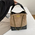 Dettaglio borsa a secchiello trapuntata marrone e nera con catena d'oro e logo in metallo - Cachi