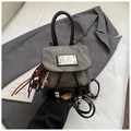 Detail of a grey denim and black glossy leather mini backpack with metal accent and tassels - Black With Pendant