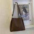 Detail einer braunen geflochtenen Ledertasche mit dekorativem Knotendesign am Riemen - Braun