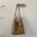 Detail of tan suede Hobo shoulder bag with round pendant and visible stitching - Khaki