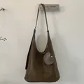 Detail view of dark brown frosted suede shoulder bag with retro circular decorative charm - Olive Green