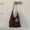 Detail of dark brown matte suede bucket bag with round charm and detachable strap - Brown