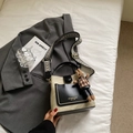 Detail of a minimalist beige leather bucket bag with geometric strap and rabbit charm - Beige Black With Pendant