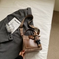 Detail view of retro bucket bag with woven strap and rabbit charm on a stylish blazer - Brown with Pendant
