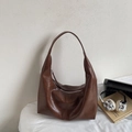 Close-up of the smooth dark brown leather texture and silver zipper detail on the tote bag - Brown