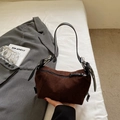Close-up of matte dark brown suede underarm bag with black leather strap and metal buckle - Brown