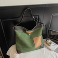 Detalle macro del bolso tote de ante verde con ribete de cuero marrón y bolsillo de contraste - Verde