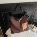 Detalle del bolso tote grande de ante marrón con correas de cuero negro y hebilla de metal - café