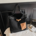 Detalle del bolso tote de ante negro con costuras en contraste y bolsillo marrón en escenario - Negro