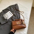 Detail of a brown faux leather crossbody bag with golden twist lock and bead tassel - Dark Brown With Pendant