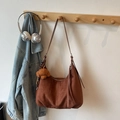 Detail of a brown suede hobo bag with long tassels and a cute plush bear charm on a rack - Brown with Pendant