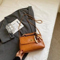 Detail of caramel brown leather handbag with golden twist lock and beaded keychain accessory - Light Brown With Pendant