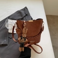 Detailed view of a brown PU leather bucket bag with a knitted bunny charm on a blazer - Brown (With Pendant)