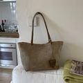 Detalle de bolso tote marrón café mate con correas delgadas sobre un sofá blanco - Caqui
