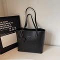 Detail view of black oil wax leather tote bag with gold logo and floral pendant charm - Black