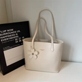 Close-up of cream tote bag with natural oil wax texture and floral charm detail - White