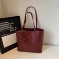 Close-up of wine red oil wax leather tote bag with fine texture and golden logo - Red