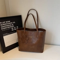 Detailed macro view of brown vintage waxed leather tote bag with floral charm and shoulder strap - Brown