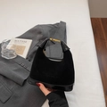 Dettaglio della borsa nera in camoscio e vernice con fibbia dorata su un abito grigio - Nero